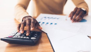 Budget Planning. Unrecognizable black businessman using calculator, tracking income and expenses. Panorama, copy space